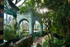 the inside of a greenhouse with lots of green plants and flowers on it's walls