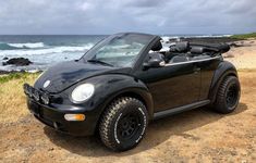 a black car parked on the side of a beach