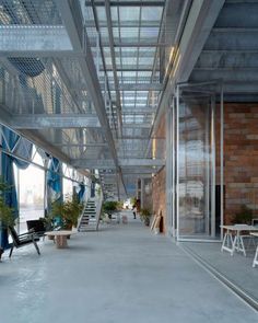 the inside of an office building with lots of windows and plants in pots on tables