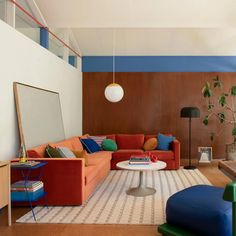 a living room filled with furniture and a white coffee table in front of a colorful wall