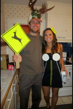 a man and woman are standing in the kitchen holding signs that read deer crossing,