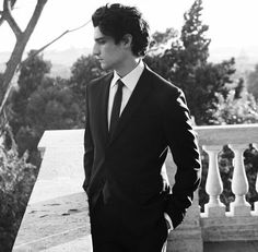 a man in a suit and tie standing on a balcony