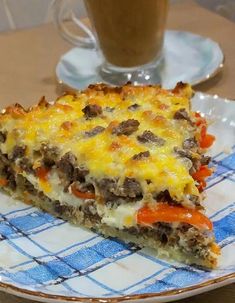 a slice of sausage and cheese pizza on a plate with a cup of coffee in the background