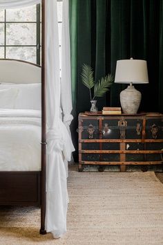 a bedroom with green curtains and a white canopy bed