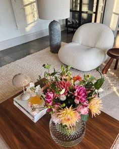 a living room with a coffee table, chair and flowers on the top of it