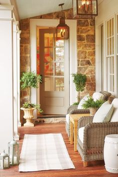 a porch with wicker furniture and potted plants on the front door sill