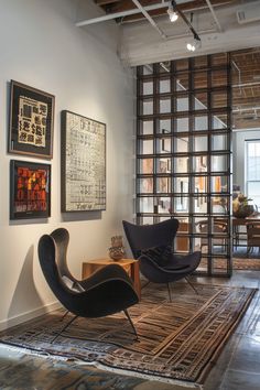 two chairs and a table in a room with pictures on the wall behind them,