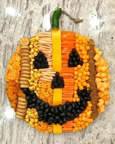 a pumpkin made out of fruits and vegetables on top of a marble surface with the word happy written in it