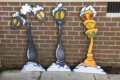 three street lamps painted on the side of a brick building, with snow falling from them