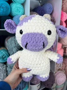 a hand holding a small stuffed animal in front of yarns and crochet