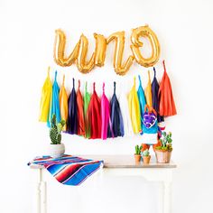 a table topped with balloons and tassels next to a wall mounted sign that says enu