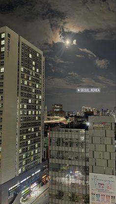 the city skyline is lit up at night, with clouds in the sky above it