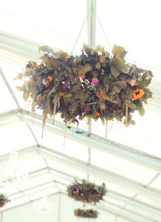 a chandelier with flowers hanging from it's sides in a white tent