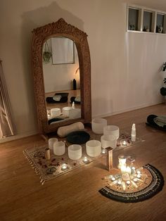 candles are arranged on the floor in front of a mirror and other items that have been placed around it