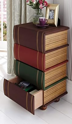 a stack of books sitting on top of a table next to a vase with flowers