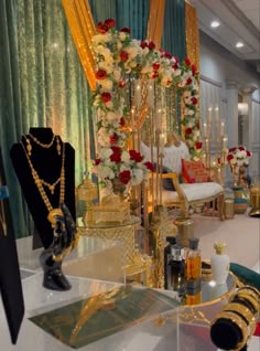 a table with gold jewelry on it and flowers in the center, surrounded by candles