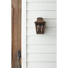 an old fashioned light on the side of a white house with wood door and window frame