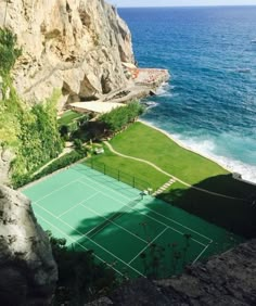 an aerial view of a tennis court on the edge of a cliff overlooking the ocean