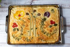 a baked dish with flowers and herbs on it