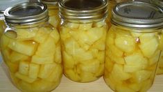 four jars filled with pickles sitting on top of a table