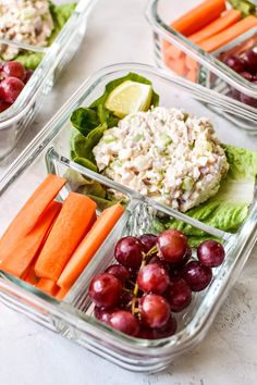 three glass containers filled with food on top of a white counter next to carrots and grapes