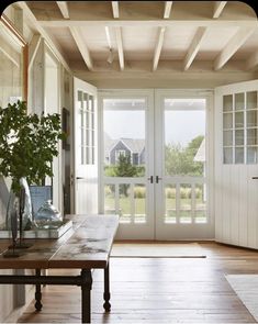 a room with wooden flooring and white doors leading to an open patio area that has french doors on both sides