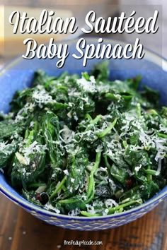 a blue bowl filled with baby spinach on top of a wooden table