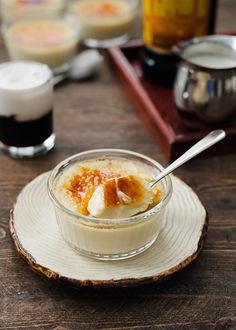 a bowl of food on top of a wooden table next to cups and saucers