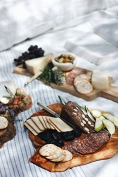 an assortment of cheeses and meats are on a wooden platter, along with other foods