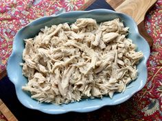 a blue bowl filled with shredded chicken on top of a table