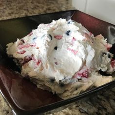 an ice cream sundae is sitting on a black plate with red, white and blue sprinkles