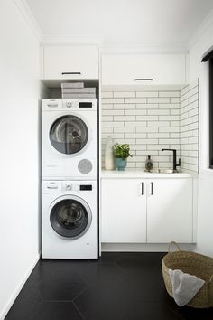 a washer and dryer in a white laundry room with black tile flooring