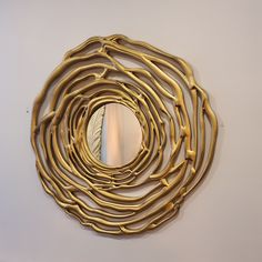 a circular mirror hanging on the wall with gold colored metal rods in front of it