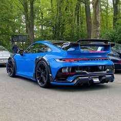 a blue sports car parked on the side of a road in front of some trees