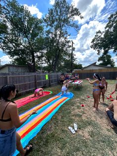 several people are sitting in the yard playing with an inflatable pool