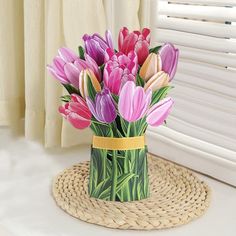 a vase filled with pink and purple flowers on top of a table next to a window