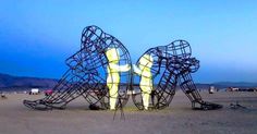 two large metal sculptures sitting on top of a sandy beach