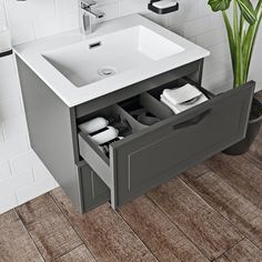 a white sink sitting under a bathroom mirror next to a wooden floor and tiled walls