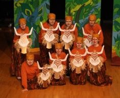 a group of people dressed in costumes posing for a photo on the stage with their heads down