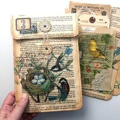 someone is holding up an old book with birds and flowers on it in their hands