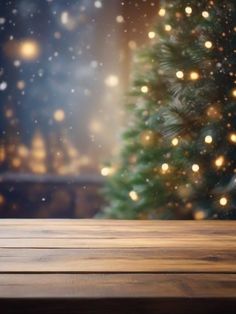 an empty wooden table in front of a christmas tree with boke lights on it