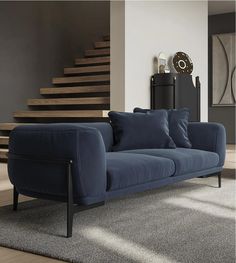 a blue couch sitting on top of a carpeted floor next to a stair case