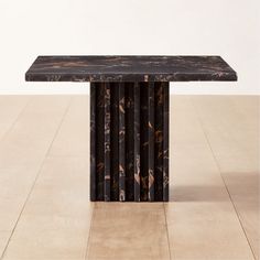 a black marble table sitting on top of a hard wood floor next to a white wall