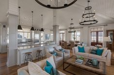 a living room filled with furniture next to a kitchen and dining room table covered in blue pillows