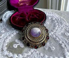 Featuring an amazing vintage Estate Spanish Austro-Hungarian Bohemian Etruscan revival sterling silver gold rolled ornate filigree brooch adorned with a luminous marbled Amethyst Cabochon, flanked by genuine rose cut bezel set garnets.  Brooch measures approximately 1.9 inches in diameter at 11.6 grams respectively and is in excellent antique condition with a functional clasp, normal wear with all stones intact and accounted for. Hallmarked STERLING/SPAIN on the reverse .  Rare and extremely collectible this is a wonderful wearable piece. Please feel free to contact me with any questions or suggestions I'm always learning  (Box not included) Austro Hungarian, Bezel Setting, Rose Cut, Garnet, Silver Gold, Amethyst, Stamp, Sterling Silver, Etsy Uk