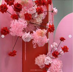 pink, red and white flowers are hanging from the ceiling in front of a mirror