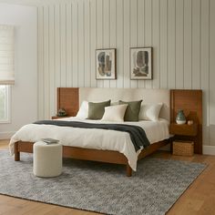 a bedroom with white walls and wood furniture, including a large bed that has two framed pictures on the wall above it