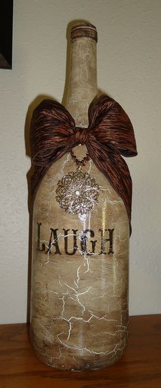 a bottle with a bow on it sitting on top of a wooden table next to a wall