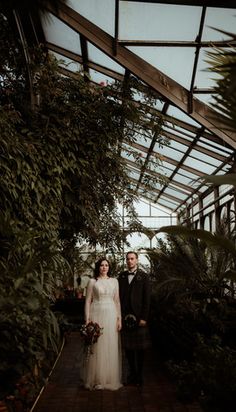 a bride and groom are standing in the greenhouse