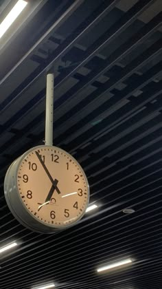 a clock hanging from the ceiling in a train station with lights on it's sides